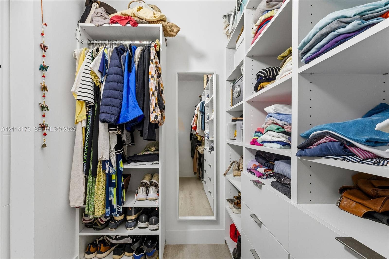 701 Brickell Key Boulevard, #1012, Miami, FL 33131 Walk-in closet featuring extensive built-in white shelving, integrated clothing rods, multiple pull-out drawers with metal hardware, and a full-length wall-mounted mirror