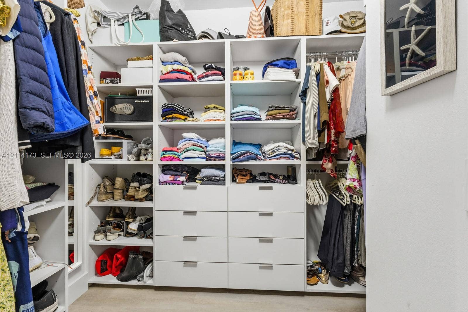 701 Brickell Key Boulevard, #1012, Miami, FL 33131 Custom walk-in closet featuring floor-to-ceiling white shelving, integrated hanging rods, eight pull-out storage drawers, and sleek metal hardware