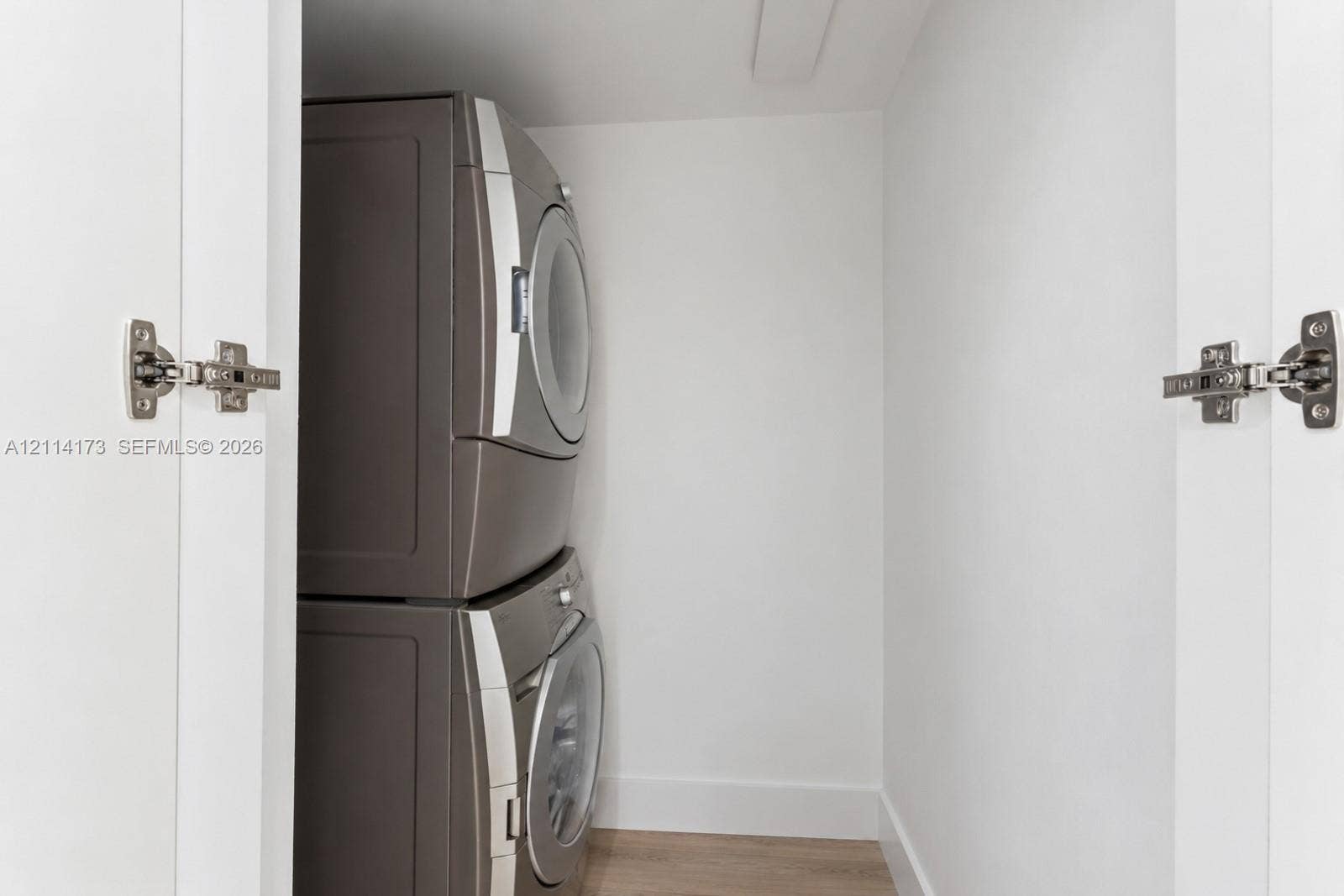 701 Brickell Key Boulevard, #1012, Miami, FL 33131 Laundry closet featuring stacked metallic-finish appliances and white cabinetry doors with chrome-finish concealed hinges