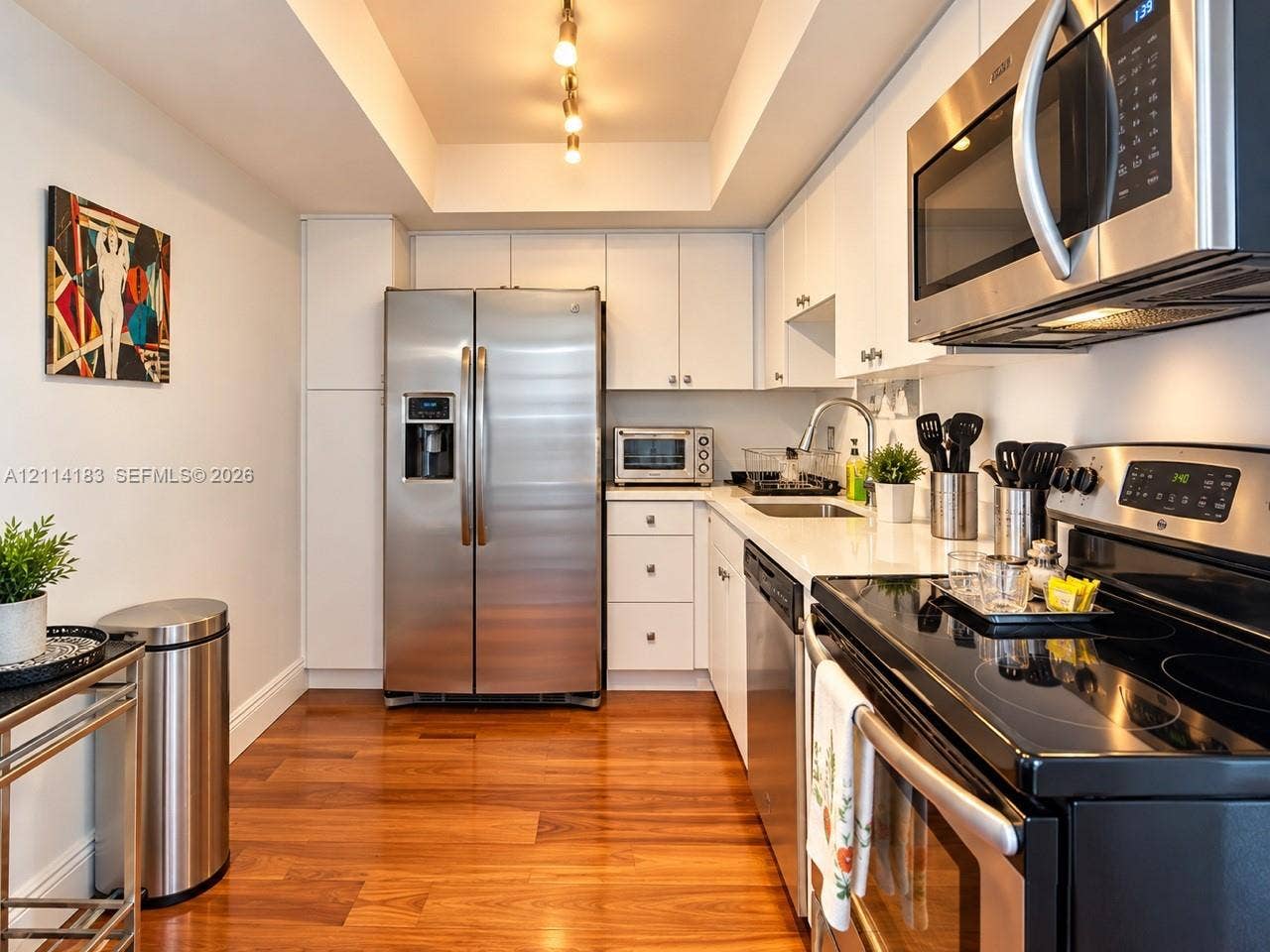 20379 W Country Club Drive, #938, Aventura, FL 33180 Kitchen featuring white cabinetry, solid-surface countertops, stainless steel appliances, recessed ceiling lighting, and wood-finish flooring
