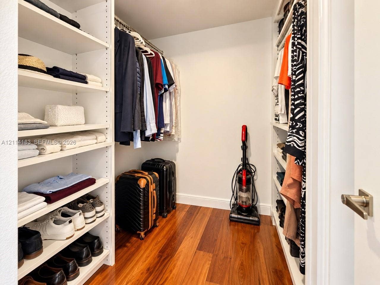 20379 W Country Club Drive, #938, Aventura, FL 33180 Walk-in closet featuring floor-to-ceiling built-in white shelving, integrated hanging rods, and wood-finish flooring