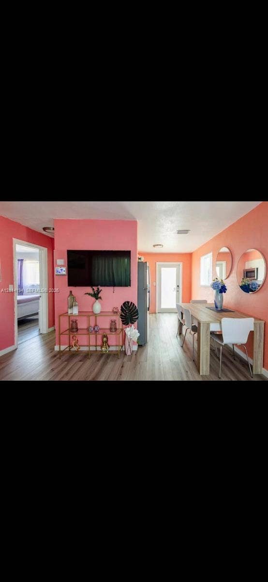 Wood-finish flooring throughout, dual wall-mounted circular mirrors, and a glass-paneled exterior door