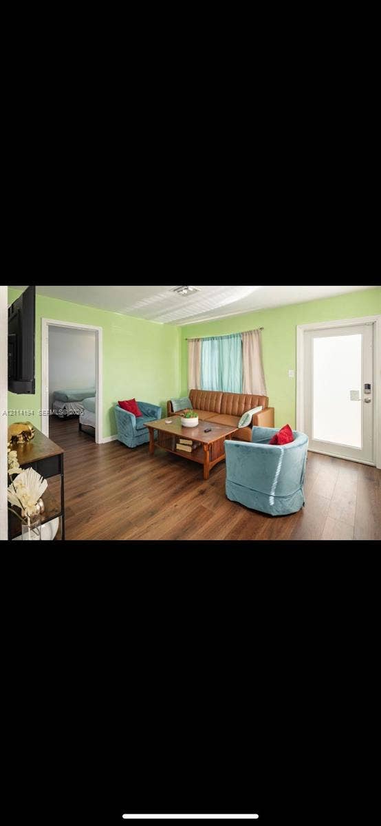 Living space featuring wood-finish flooring, a full-lite glass exterior door, and a wide doorway