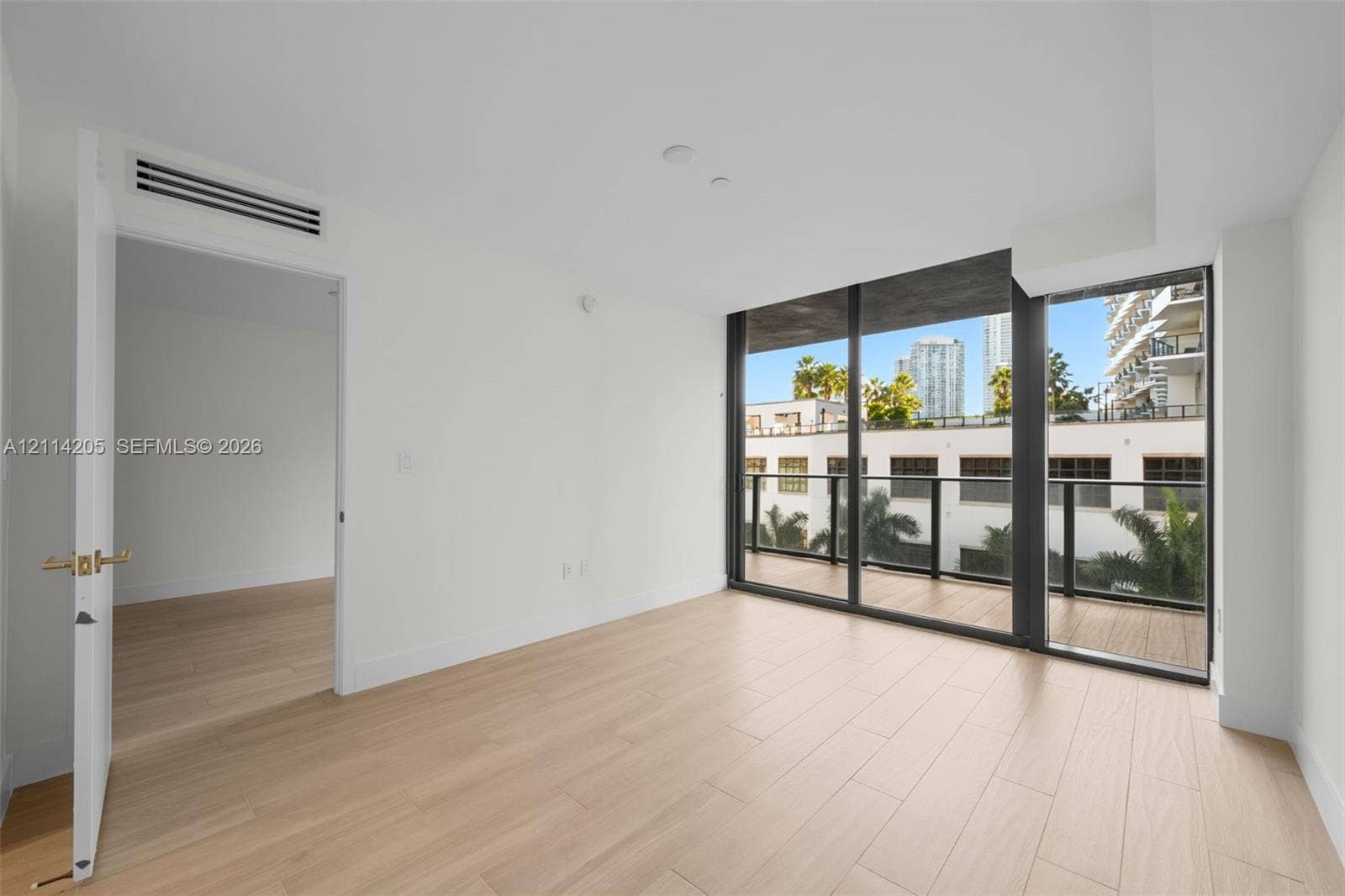 Interior space featuring wood-finish flooring, floor-to-ceiling windows, and a private balcony with a dark metal railing