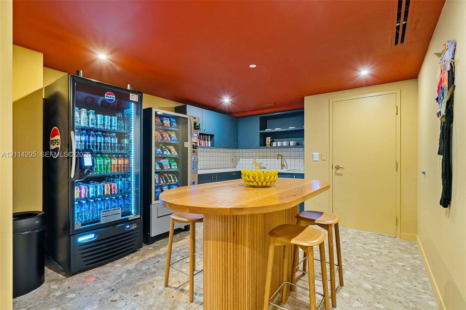 Built-in cabinetry with integrated shelving, matte-finish square tile backsplash, metallic sink faucet, and stone-finish tile flooring - building amenity