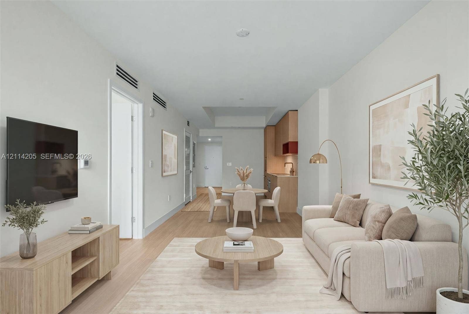 Open-concept interior featuring light wood-finish flooring, recessed lighting, and a modern kitchen with flat-panel cabinetry - staged