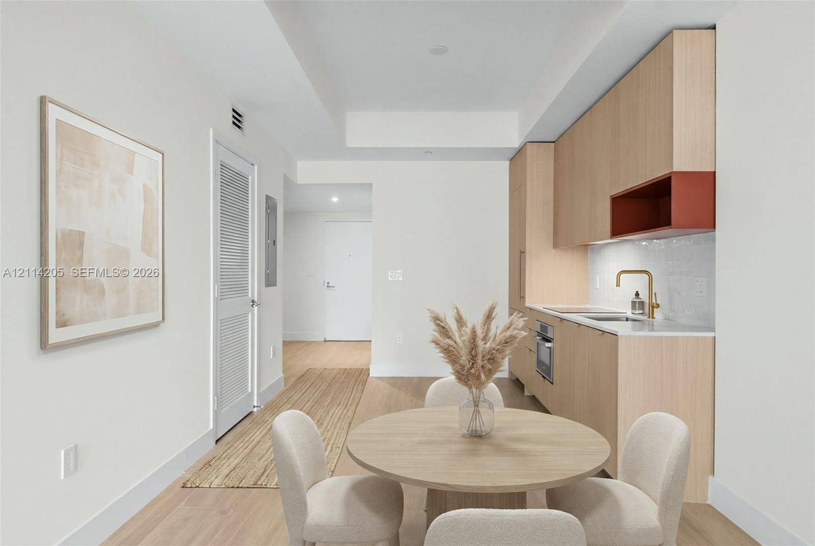 Kitchen featuring light wood-finish cabinetry, an integrated cooktop, a built-in oven, a brass-tone faucet, and a stone-finish countertop - staged