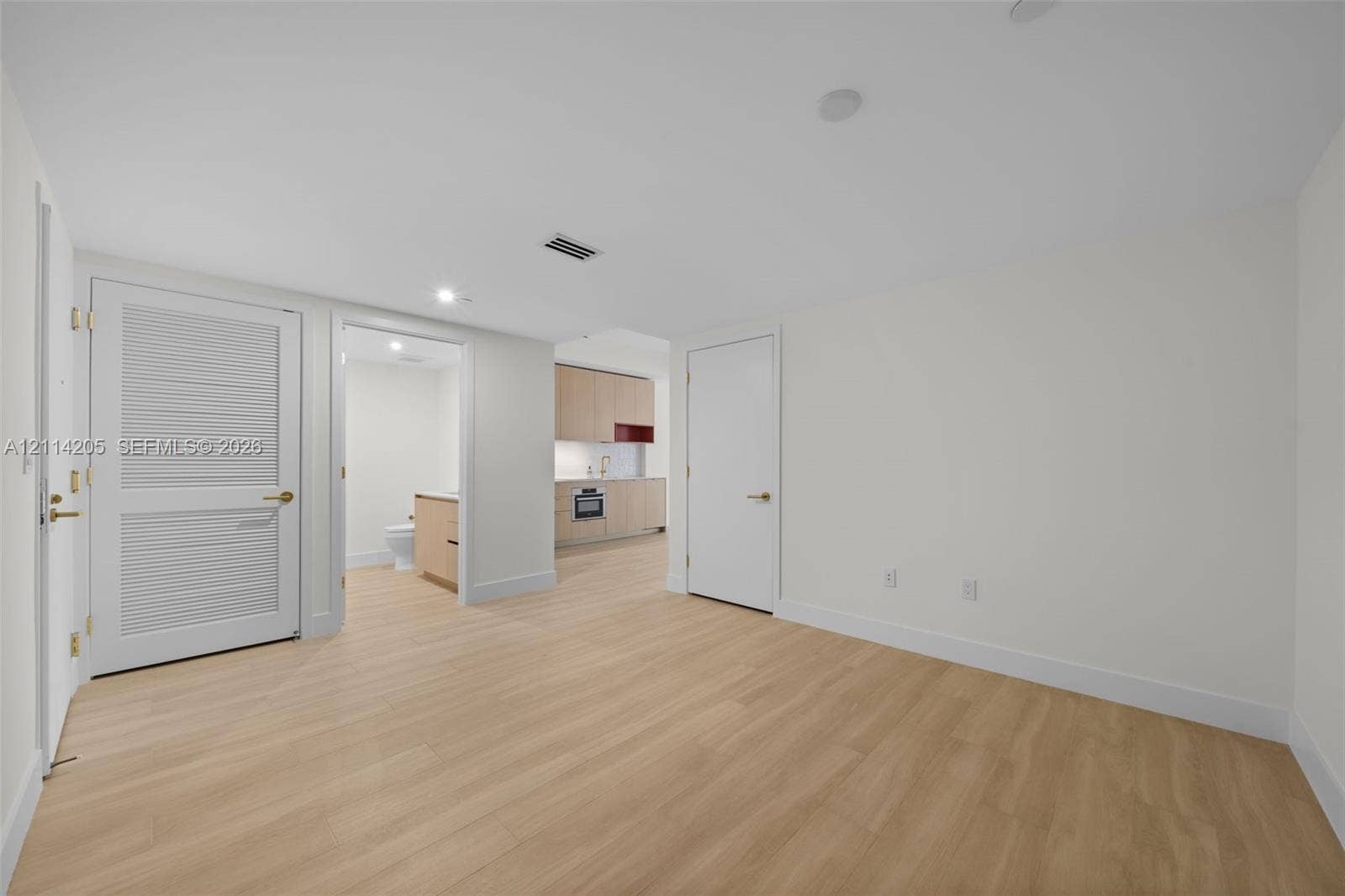 Neutral interior featuring light-tone wood-finish flooring, recessed ceiling lighting, and solid-core paneled doors