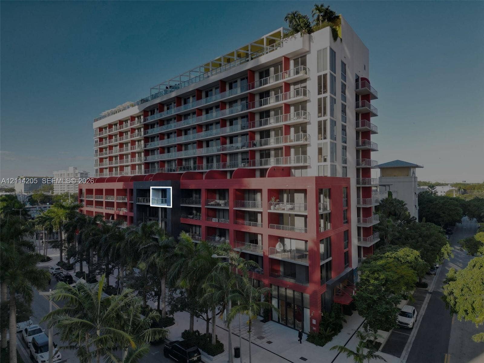 Multi-story residential complex featuring private balconies, floor-to-ceiling glass windows, rooftop terrace, and palm-lined exterior grounds
