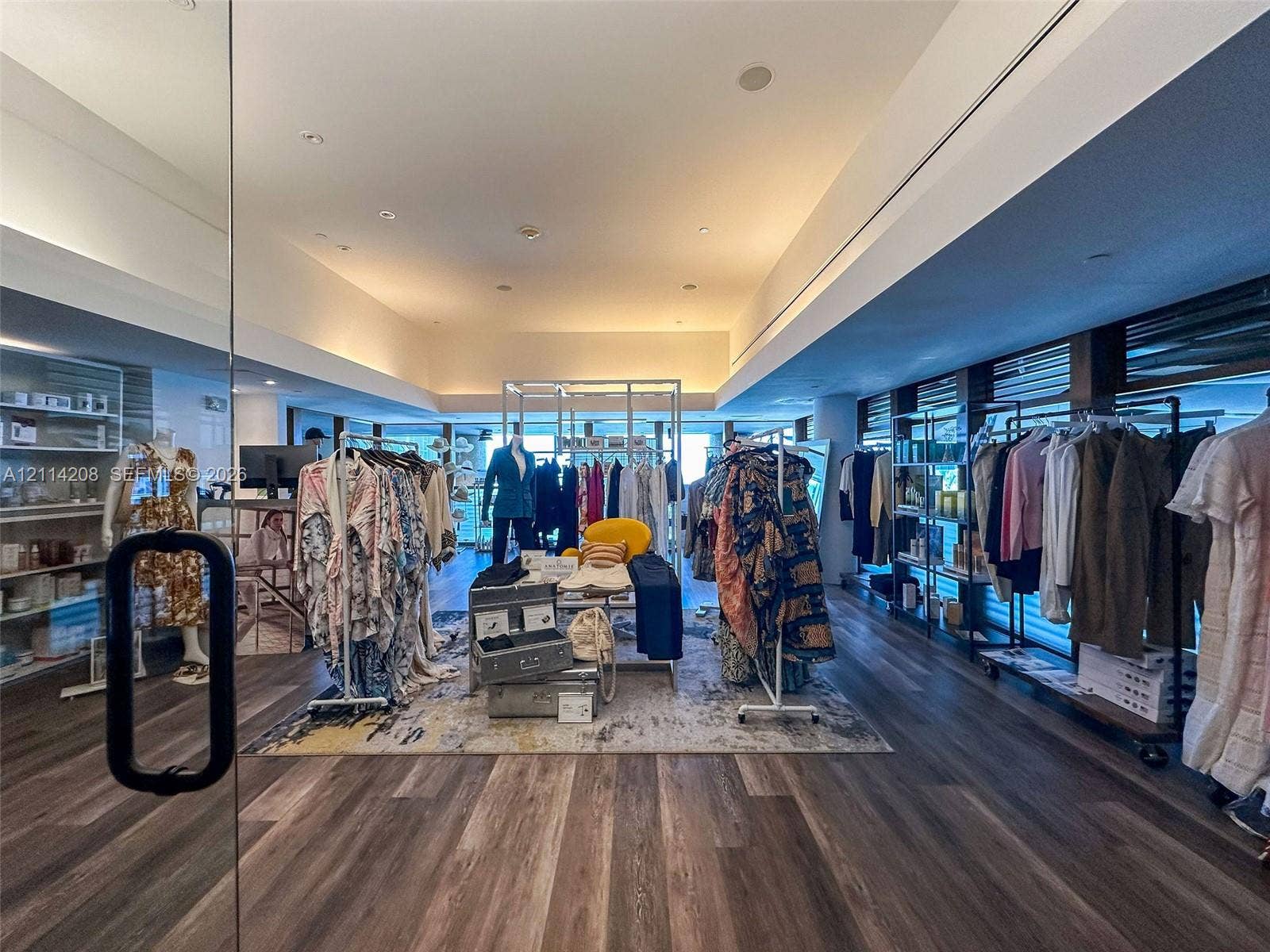 6801 Collins Avenue, #604, Miami Beach, FL 33141 Expansive interior space featuring recessed lighting, wood-finish flooring, floor-to-ceiling glass storefront, and built-in wall shelving