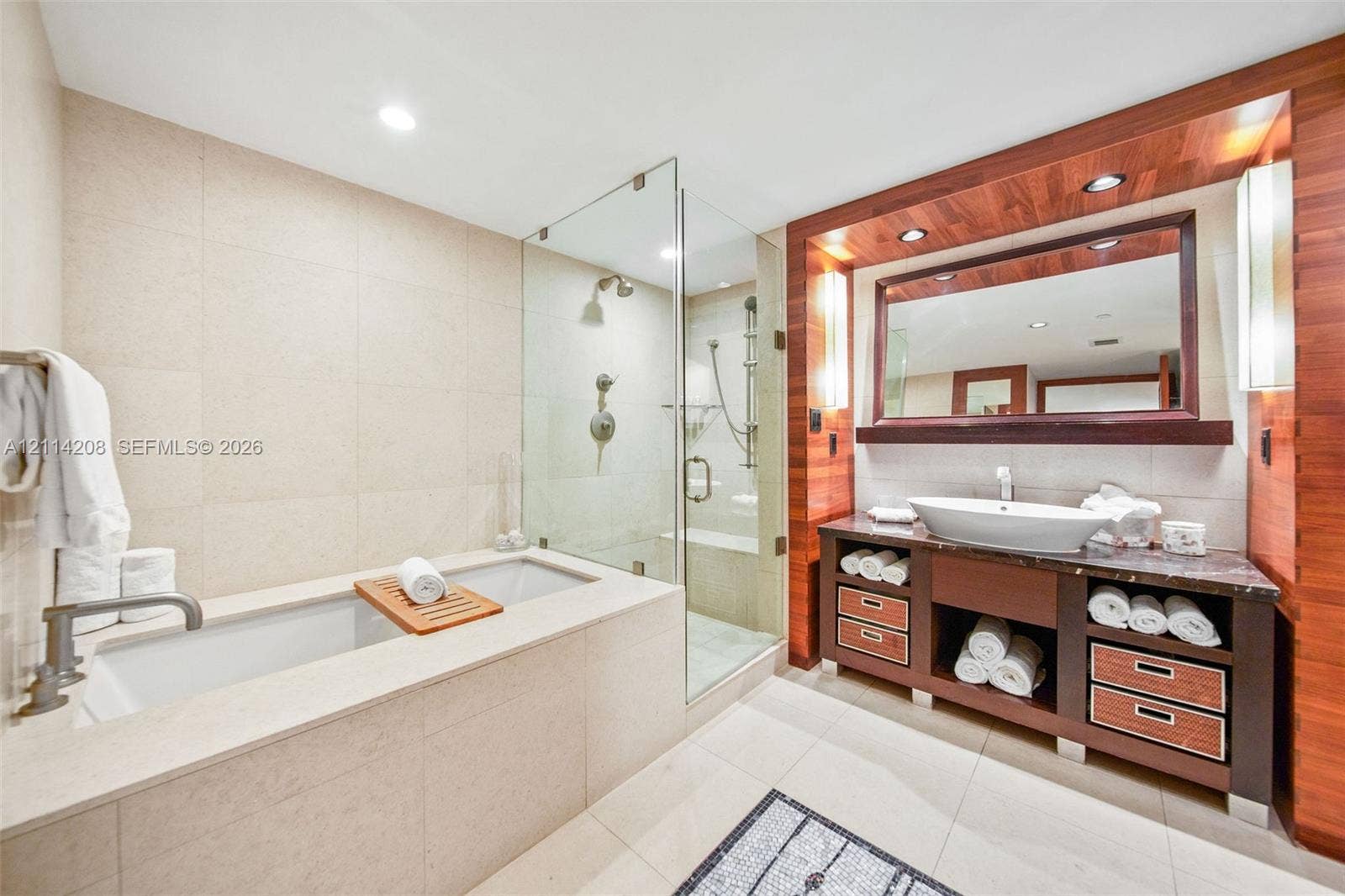 6801 Collins Avenue, #604, Miami Beach, FL 33141 Bathroom featuring a built-in stone-surround tub, glass-enclosed shower with handheld fixture, wood-paneled vanity with integrated vessel sink, and recessed lighting