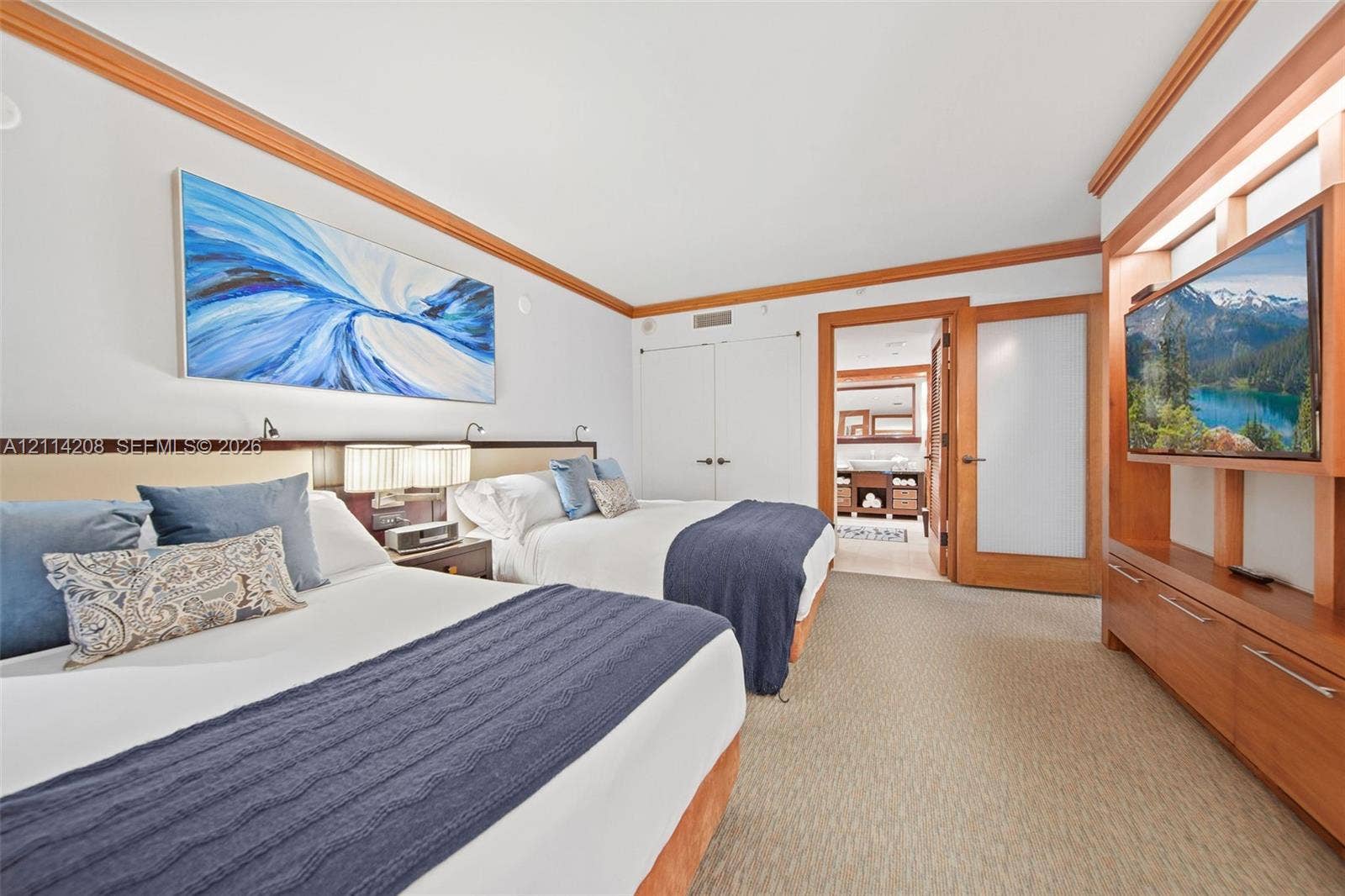 6801 Collins Avenue, #604, Miami Beach, FL 33141 Custom wood trim detailing, built-in wooden media cabinetry, recessed lighting, and a frosted glass-panel door