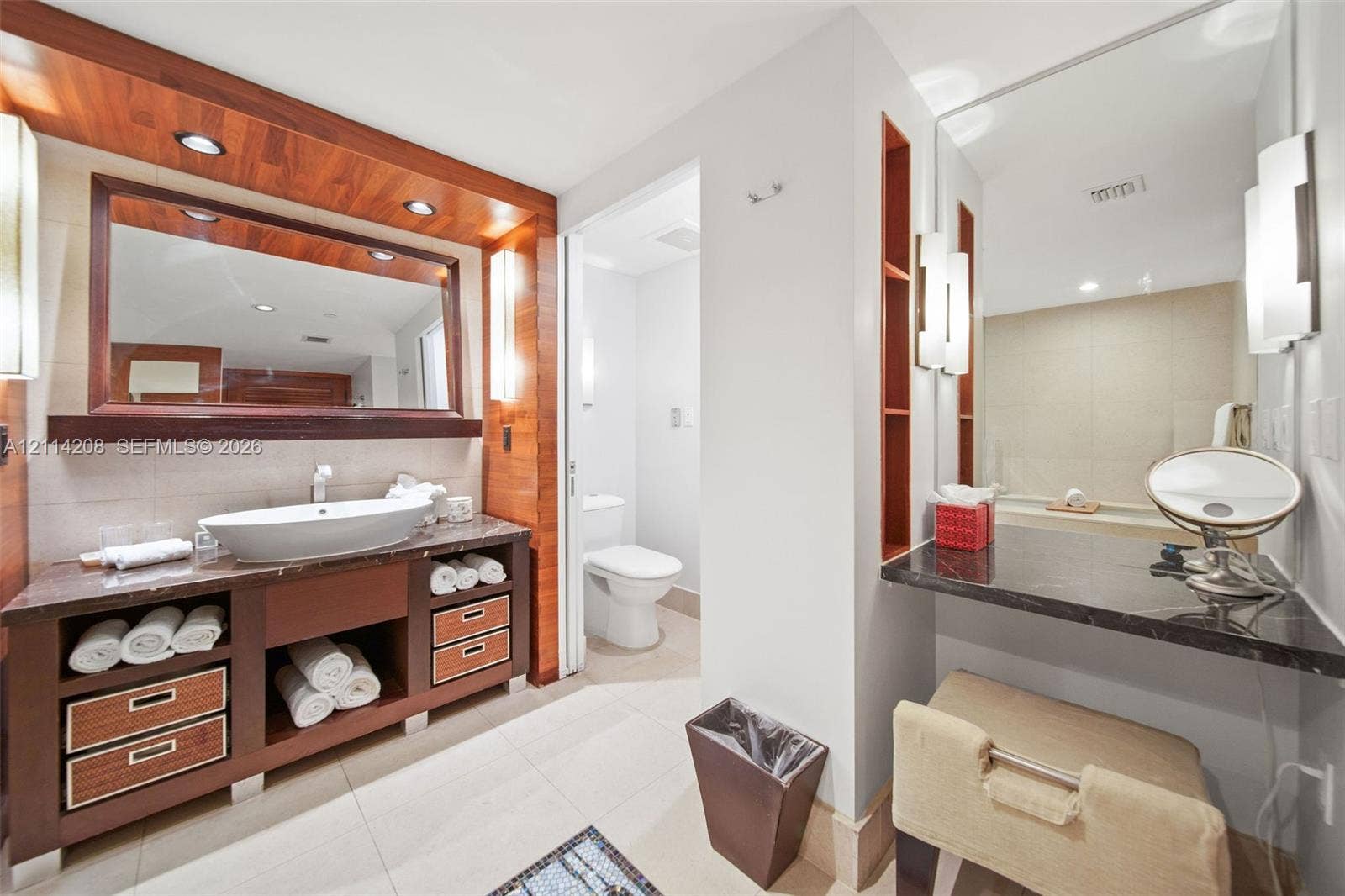 6801 Collins Avenue, #604, Miami Beach, FL 33141 Custom wood-finish vanity with integrated storage, vessel sink, stone countertop, built-in shelving, and recessed lighting