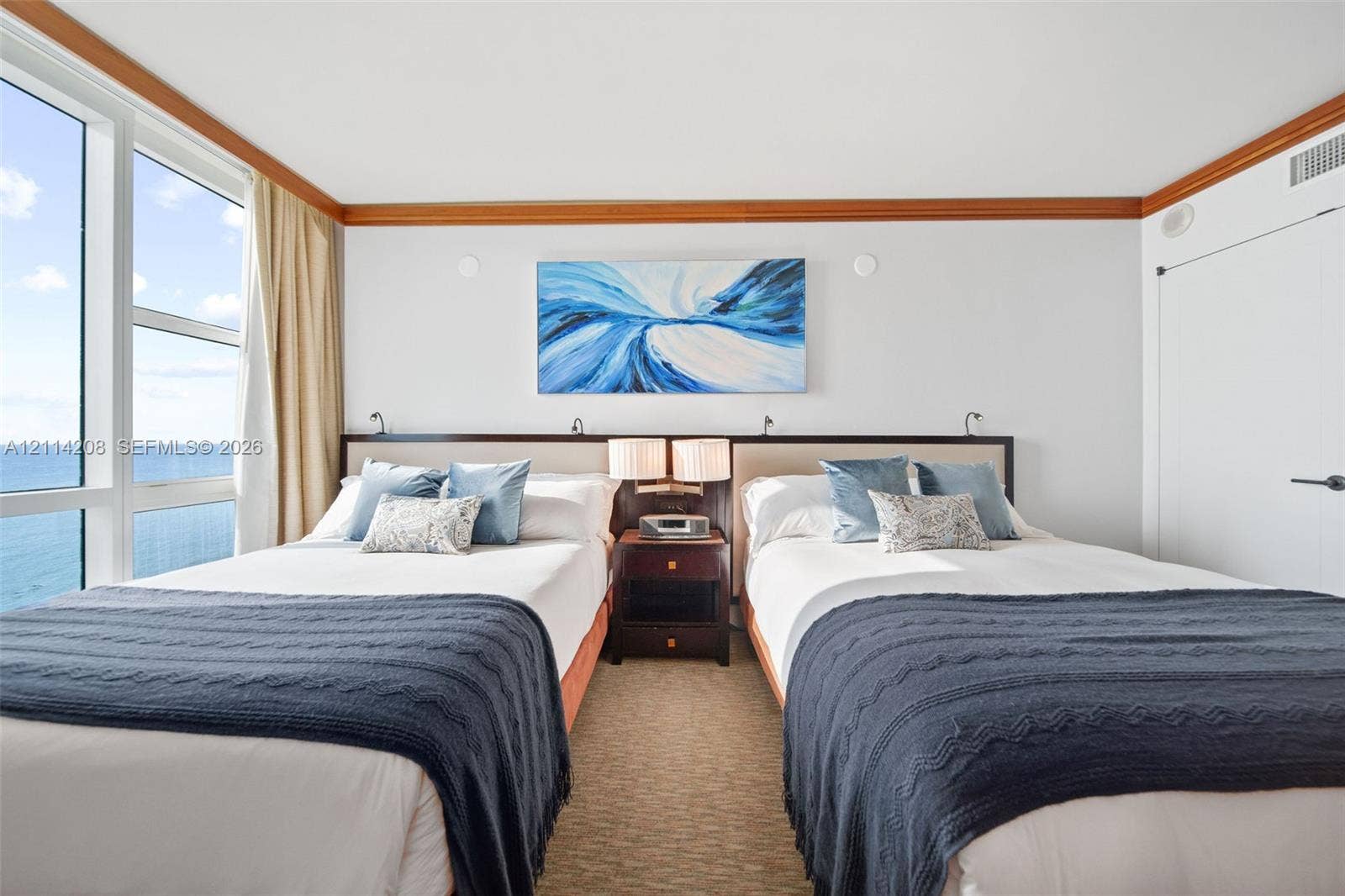 6801 Collins Avenue, #604, Miami Beach, FL 33141 Floor-to-ceiling windows with ocean scenery, wood-trim crown molding, and neutral textured wall-to-wall carpeting