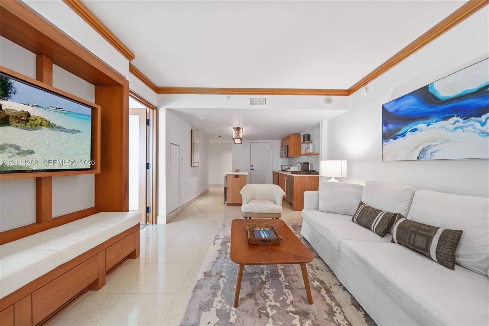 6801 Collins Avenue, #604, Miami Beach, FL 33141 Custom built-in wood media console with integrated shelving, crown molding, tile flooring, and kitchen cabinetry