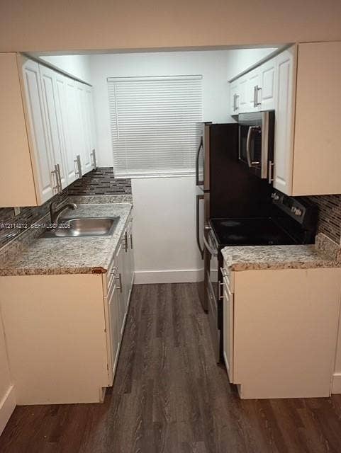 Kitchen featuring white cabinetry, stone-finish countertops, decorative tile backsplash, stainless steel appliances, and wood-finish flooring