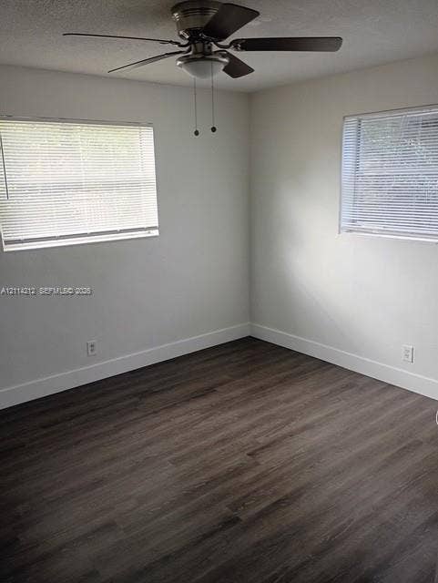 Room featuring wood-finish flooring, a ceiling fan with integrated lighting, and dual windows with horizontal blinds