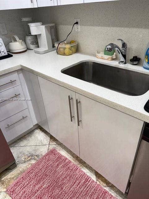 3701 N Country Club Drive, #706, Aventura, FL 33180 Glossy white cabinetry with modern metal pulls, light-toned composite countertops, undermount stainless steel sink, and polished chrome faucet