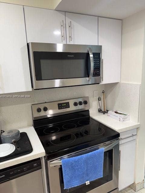 3701 N Country Club Drive, #706, Aventura, FL 33180 Kitchen featuring white slab-front cabinetry, stainless steel over-the-range microwave, stainless steel electric range with smooth cooktop, and stone-finish countertops
