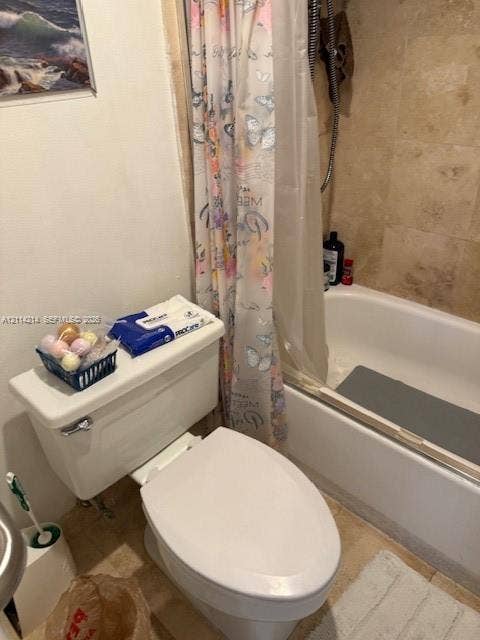3701 N Country Club Drive, #706, Aventura, FL 33180 Bathroom featuring a standard white toilet and a built-in bathtub with neutral-toned stone-finish tile surround and a wall-mounted shower fixture