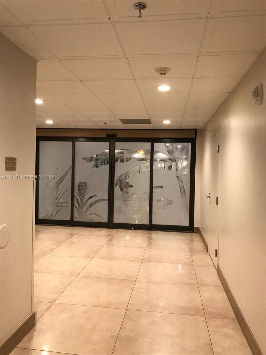3701 N Country Club Drive, #706, Aventura, FL 33180 Neutral-toned tile flooring, recessed ceiling lighting, and floor-to-ceiling glass panel doors featuring frosted botanical-patterned detailing