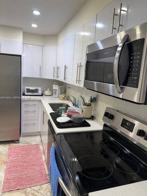 3701 N Country Club Drive, #706, Aventura, FL 33180 Kitchen featuring high-gloss white cabinetry, solid surface countertops, stainless steel appliances, and tiled flooring