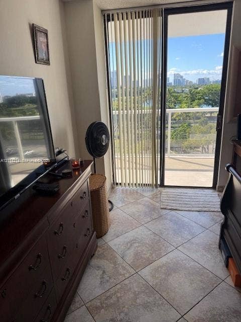 3701 N Country Club Drive, #706, Aventura, FL 33180 Ceramic tile flooring, sliding glass door with vertical blinds, and a private balcony featuring a skyline and landscape backdrop