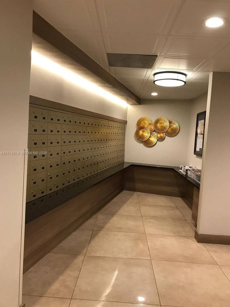 3701 N Country Club Drive, #706, Aventura, FL 33180 Mail center featuring integrated metallic mailboxes, recessed ceiling lighting, wall-mounted ambient lighting, neutral tile flooring, and custom cabinetry