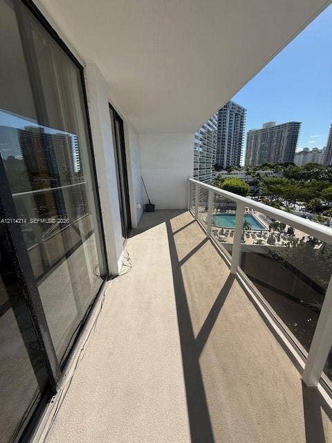 3701 N Country Club Drive, #706, Aventura, FL 33180 Covered outdoor balcony featuring a concrete floor, glass-paneled railing, and dual sliding glass door access