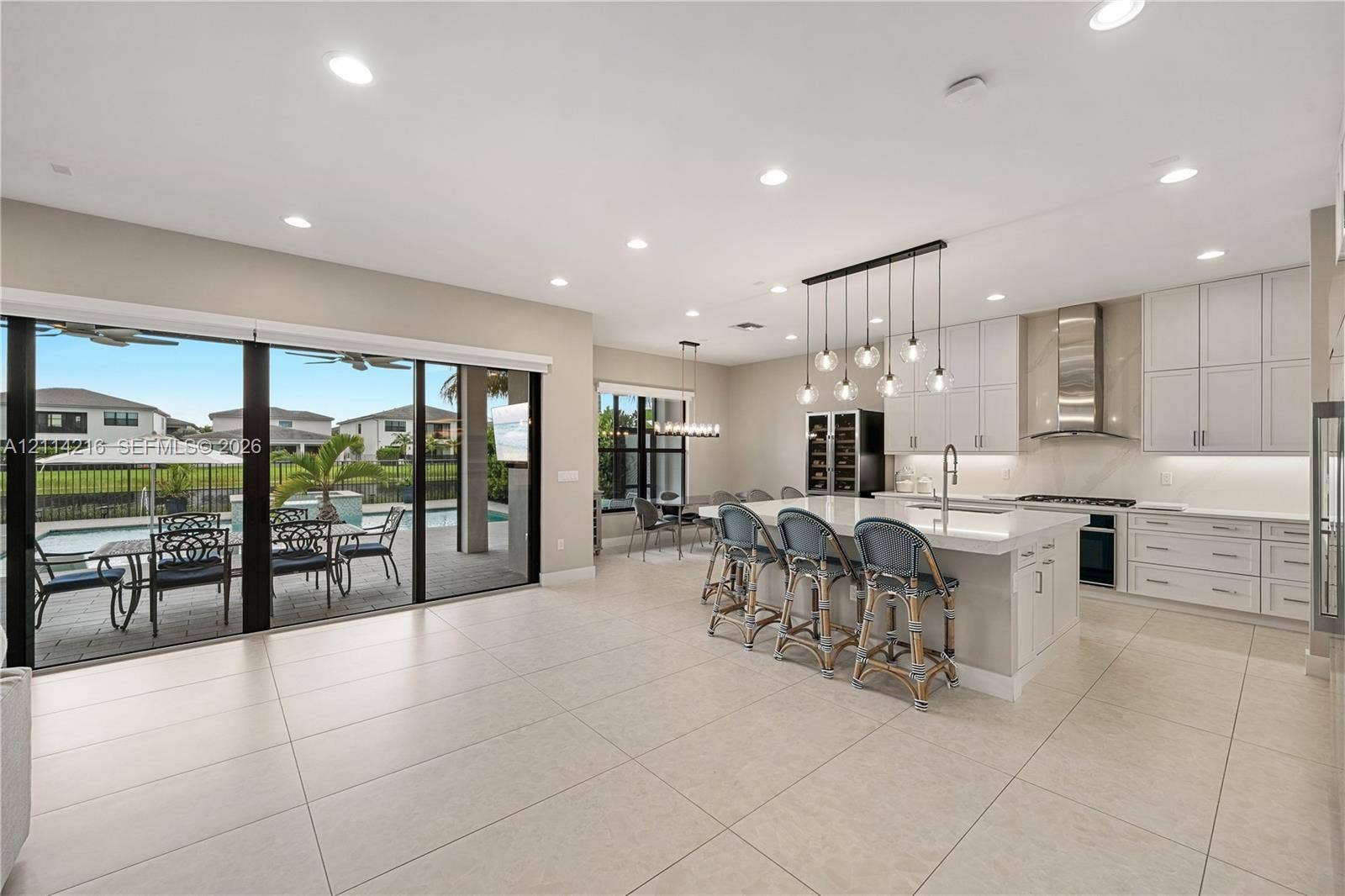17085 Teton River Road, Boca Raton, FL 33496 Kitchen featuring shaker-style cabinetry, quartz countertops, a stainless steel range hood, integrated wine storage, and oversized sliding glass doors