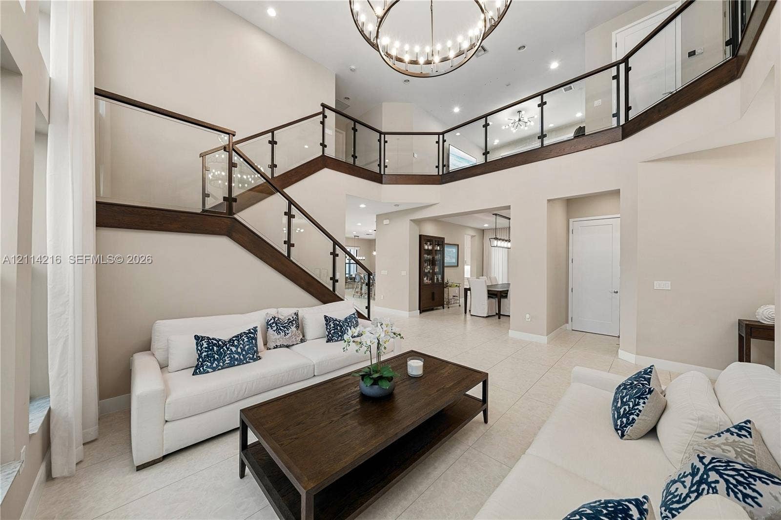 17085 Teton River Road, Boca Raton, FL 33496 Two-story foyer featuring high ceilings, open-concept balcony with glass railings, wood-cased staircase, circular tiered chandelier, and tile flooring