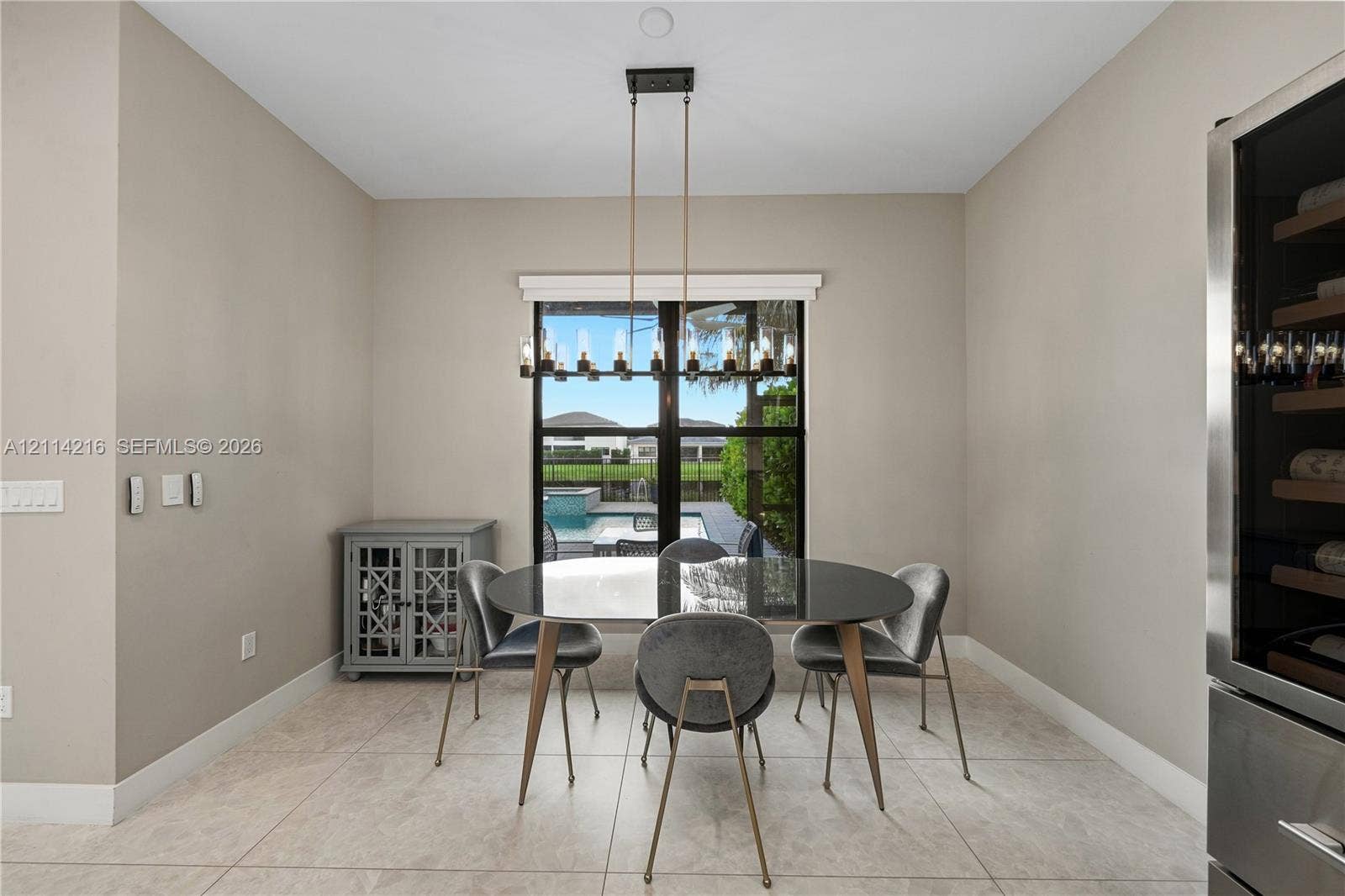 17085 Teton River Road, Boca Raton, FL 33496 Dining area featuring large-format tile flooring, a linear multi-light pendant fixture, and a built-in stainless steel wine refrigerator