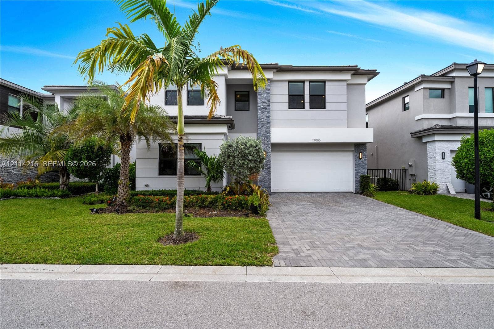 17085 Teton River Road, Boca Raton, FL 33496 Two-story contemporary exterior featuring stone veneer accents, multi-pane windows, a paved driveway, and mature landscaping