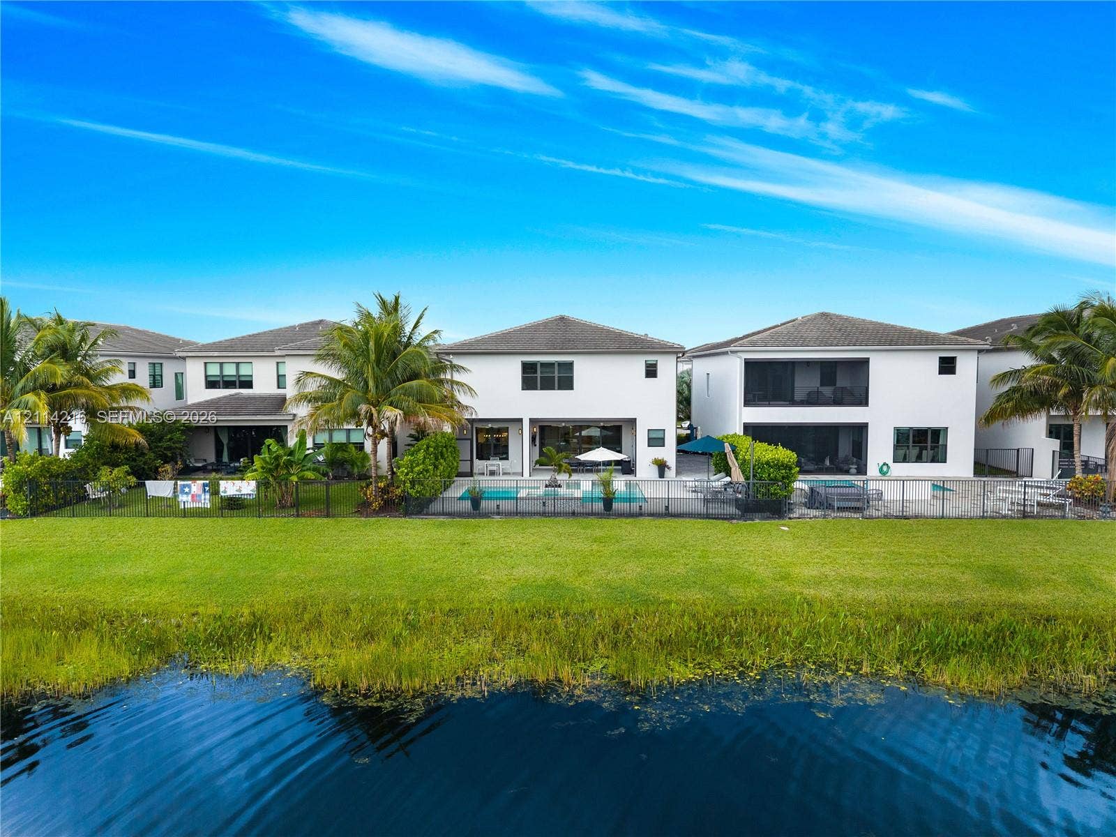 17085 Teton River Road, Boca Raton, FL 33496 Waterfront property featuring a private swimming pool, screen-enclosed patio, and manicured lawn