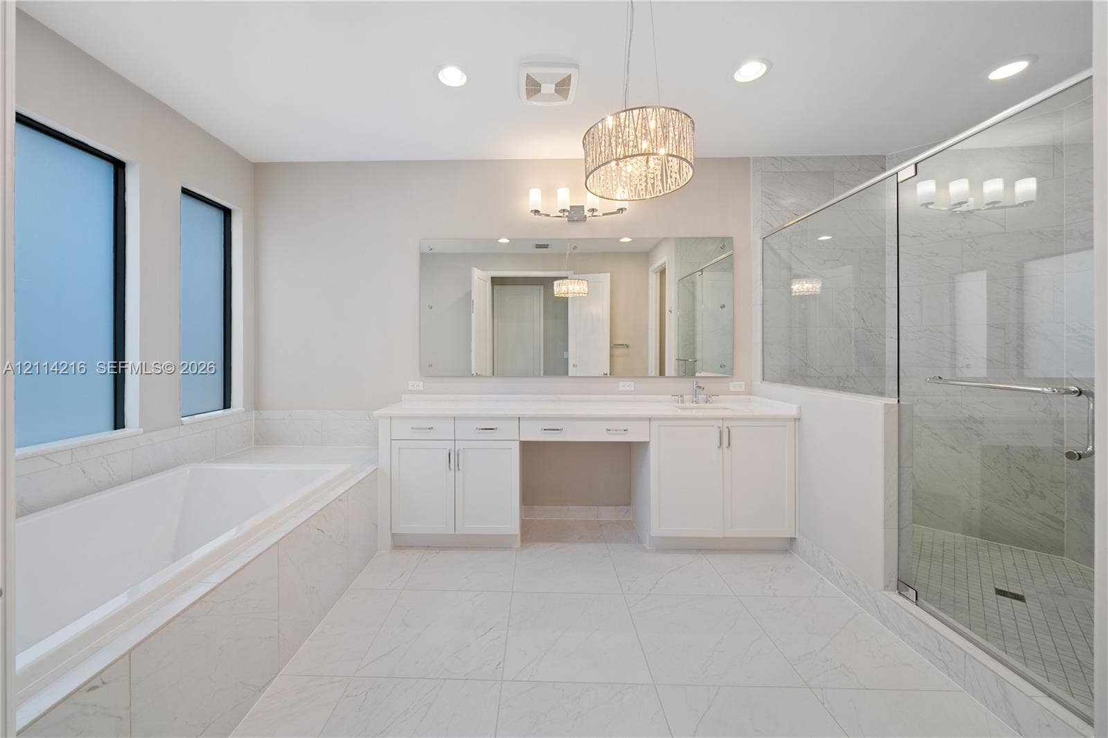 17085 Teton River Road, Boca Raton, FL 33496 Bathroom featuring a walk-in shower with glass enclosure, soaking tub with tile surround, white cabinetry, integrated vanity, and decorative pendant lighting