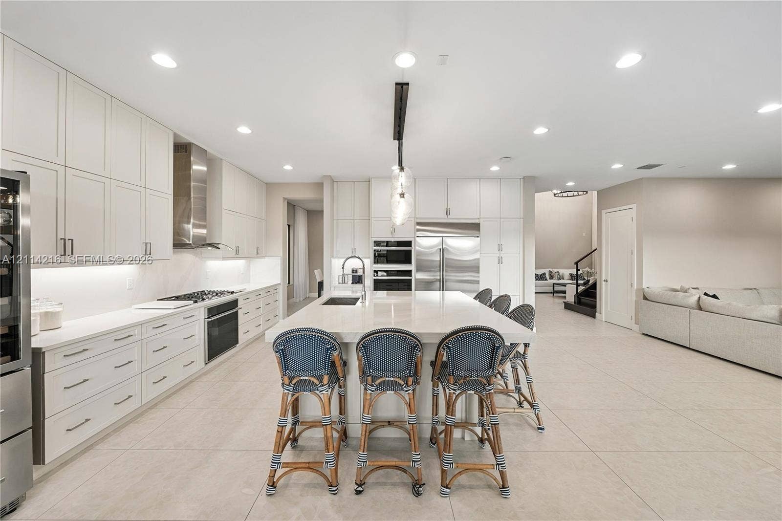 17085 Teton River Road, Boca Raton, FL 33496 Contemporary kitchen featuring ceiling-height flat-panel cabinetry, a central island with a stone-finish countertop, stainless steel built-in appliances, recessed lighting, and large-format tile flooring