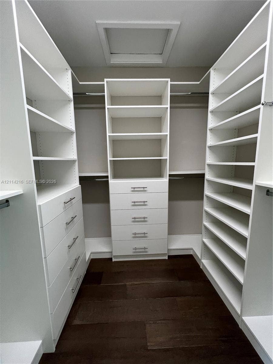 17085 Teton River Road, Boca Raton, FL 33496 Custom walk-in closet featuring extensive white built-in shelving, multiple integrated storage drawers with brushed nickel hardware, and dark wood-finish flooring