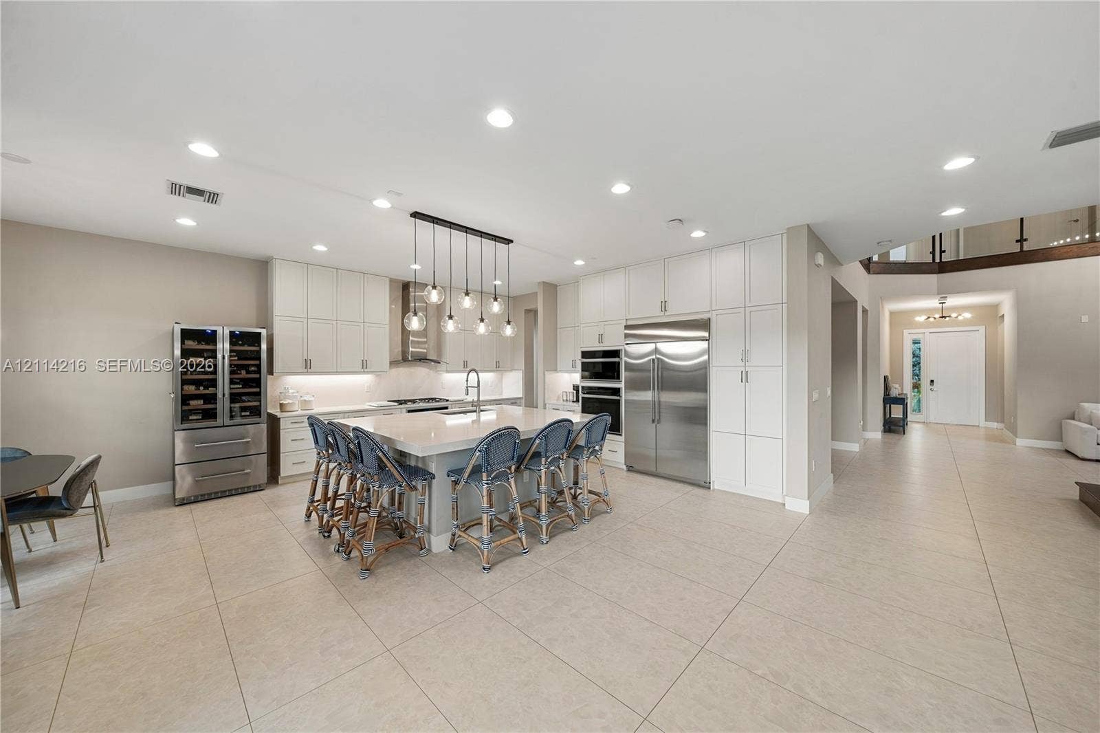 17085 Teton River Road, Boca Raton, FL 33496 Kitchen featuring floor-to-ceiling white cabinetry, a large central island with quartz countertops, integrated stainless steel appliances, built-in wine refrigeration, and recessed ceiling lighting