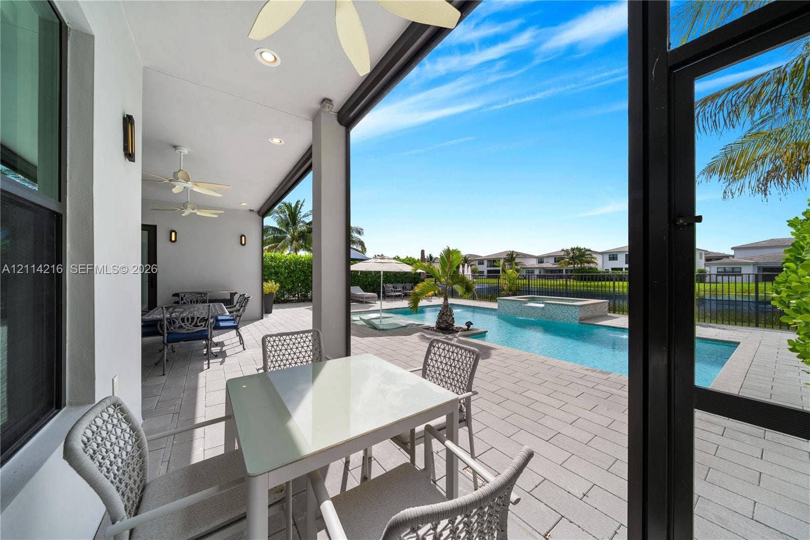 17085 Teton River Road, Boca Raton, FL 33496 Covered patio featuring recessed lighting and ceiling fans, leading to a paver pool deck, swimming pool, and integrated spa