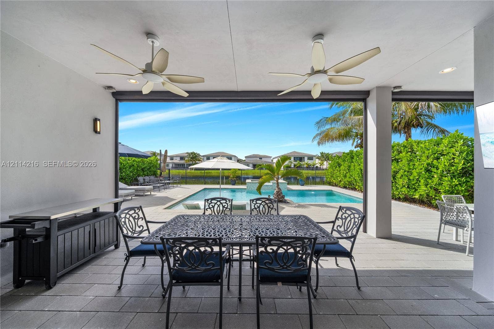 17085 Teton River Road, Boca Raton, FL 33496 Covered patio featuring large-format tile flooring, dual ceiling fans, and recessed lighting, overlooking a private swimming pool with a stone water feature