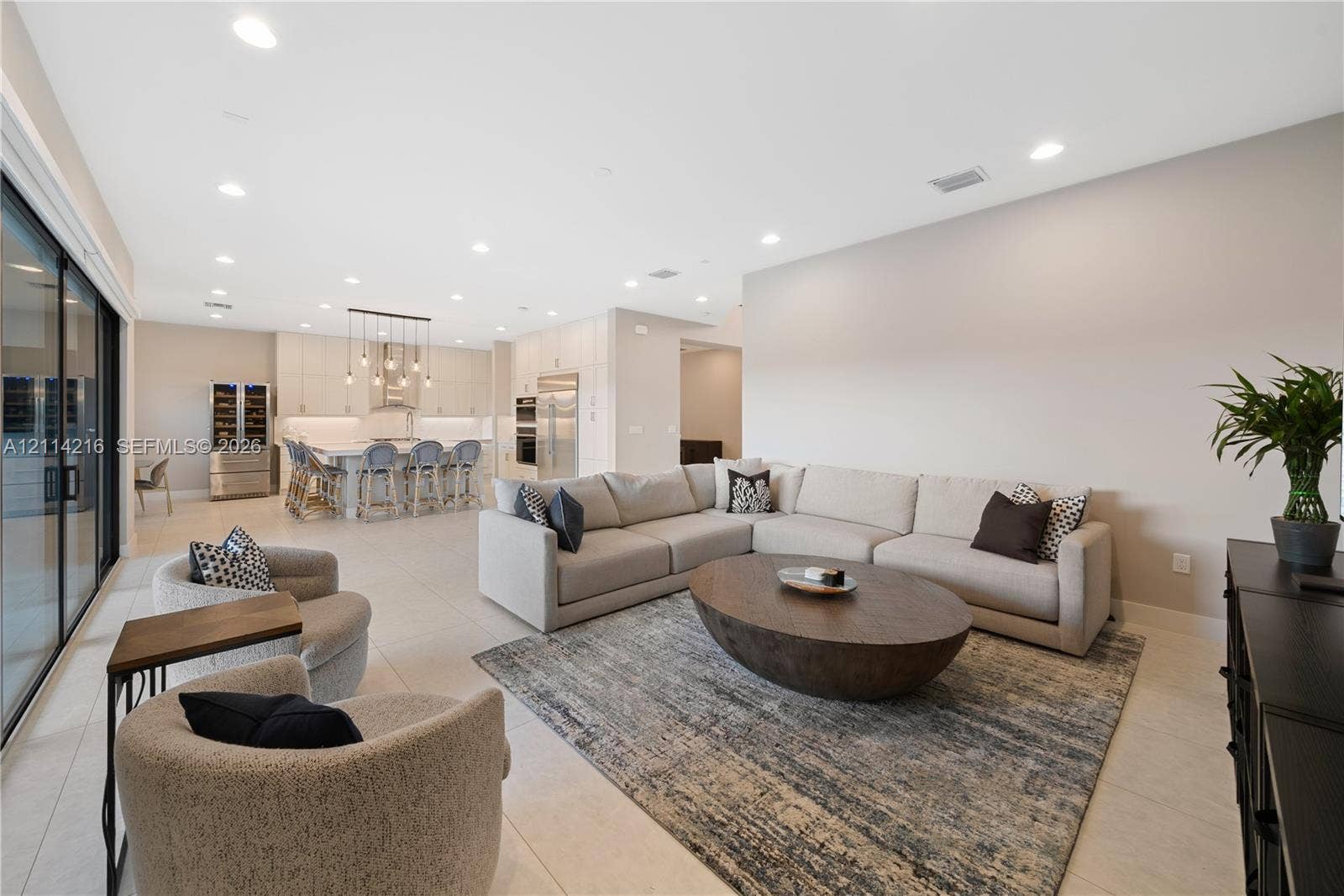 17085 Teton River Road, Boca Raton, FL 33496 Open-concept interior featuring large-format tile flooring, recessed ceiling lighting, sliding glass doors, and a kitchen equipped with a center island and built-in stainless steel appliances