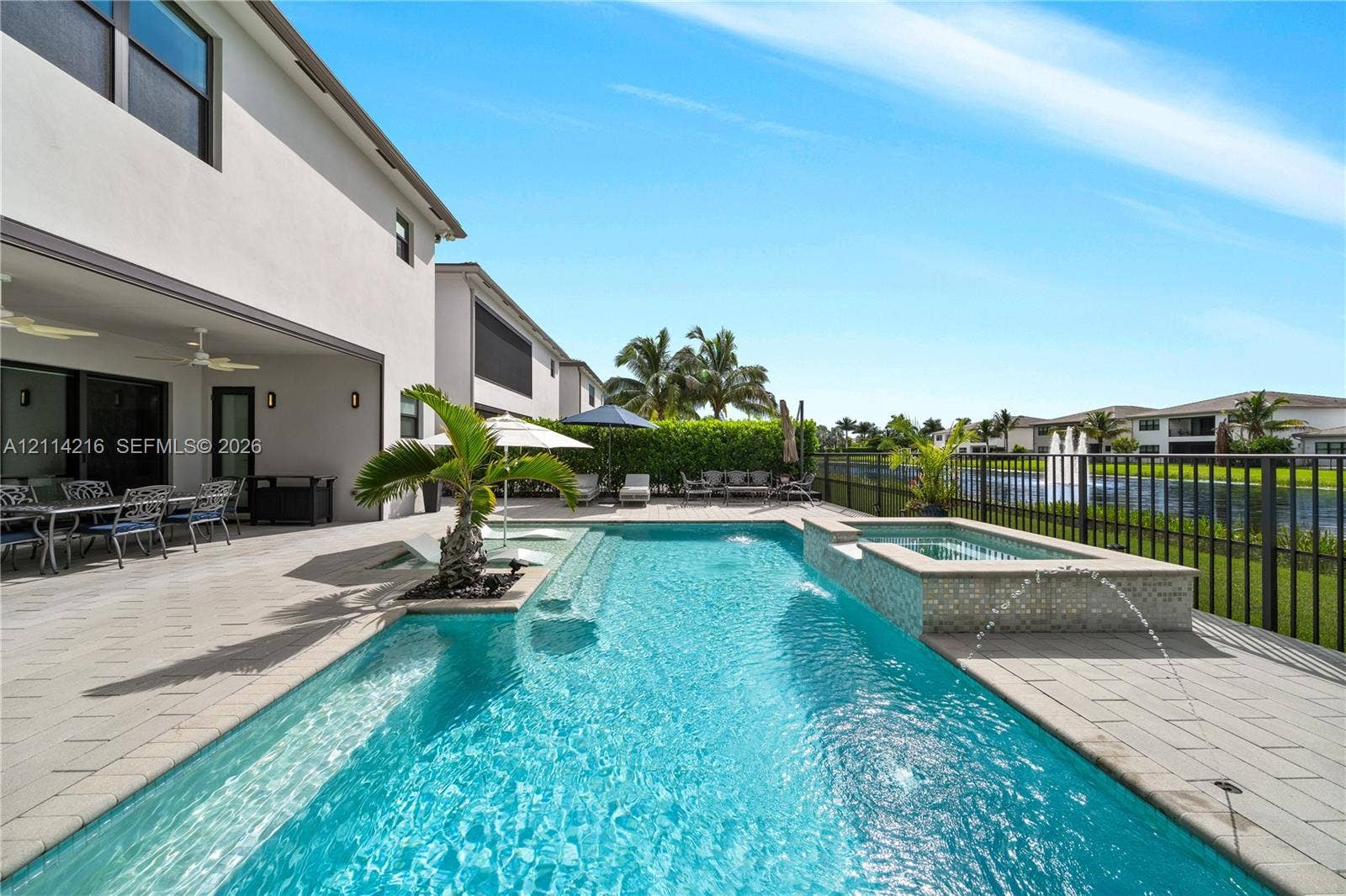 17085 Teton River Road, Boca Raton, FL 33496 Covered patio with paver flooring, custom in-ground swimming pool, elevated spa with tile finish, and water feature