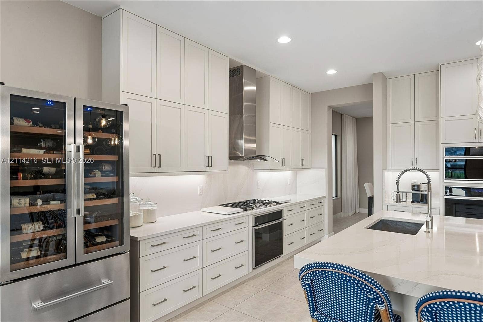 17085 Teton River Road, Boca Raton, FL 33496 Kitchen featuring white ceiling-height cabinetry, quartz countertops, stainless steel appliance suite including a built-in wine refrigerator, and a center island with a stainless steel pull-down faucet