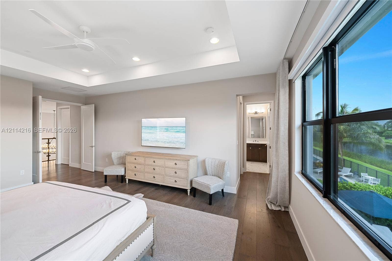 17085 Teton River Road, Boca Raton, FL 33496 Tray ceiling, wood-finish flooring, ceiling fan, and large windows with exterior water scenery
