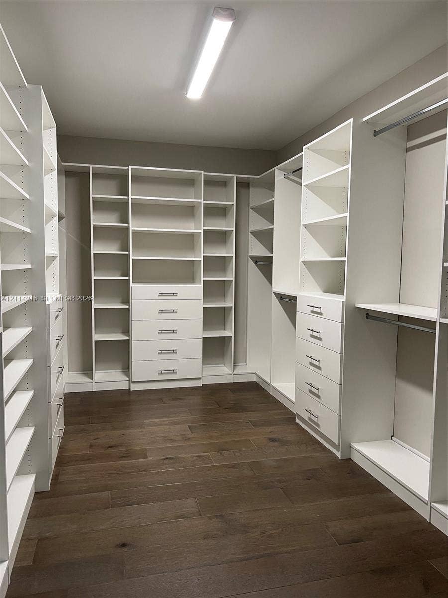 17085 Teton River Road, Boca Raton, FL 33496 Walk-in closet featuring extensive built-in white cabinetry, integrated drawer banks, adjustable shelving, chrome hardware, and wood-finish flooring