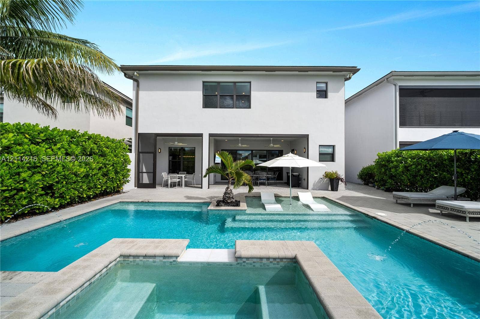 17085 Teton River Road, Boca Raton, FL 33496 Swimming pool featuring a sun shelf with water fountains, raised spill-over spa, paved deck, and a covered lanai