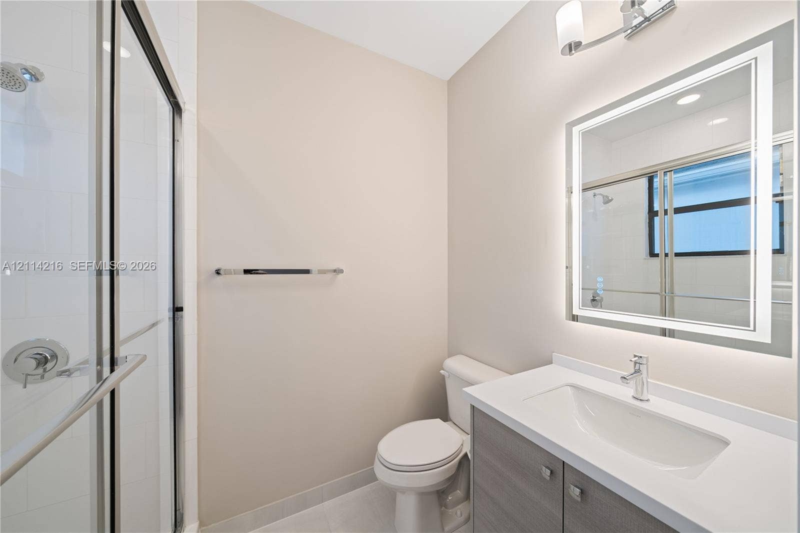 17085 Teton River Road, Boca Raton, FL 33496 Bathroom featuring a glass-enclosed shower, integrated vanity with a rectangular sink, wall-mounted illuminated mirror, and polished chrome hardware