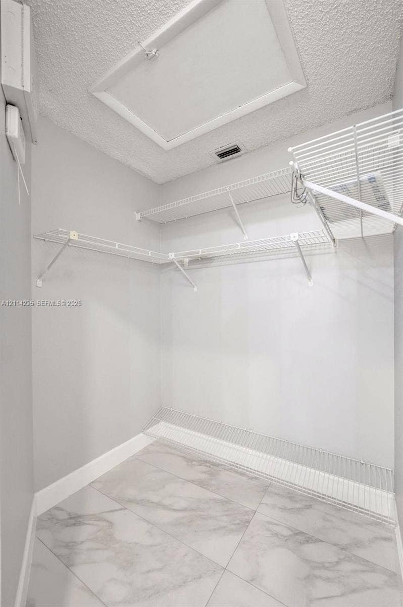 5741 SW 88th Terrace, Cooper City, FL 33328 Storage area featuring large-format tile flooring, multi-level white wire shelving, and attic access panel