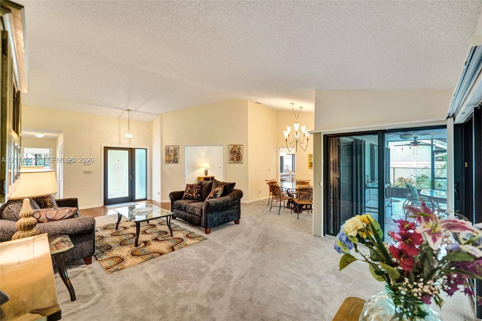 5741 SW 88th Terrace, Cooper City, FL 33328 Vaulted ceilings, sliding glass doors, multi-light chandelier, front entryway with side-light panels, and neutral carpeting