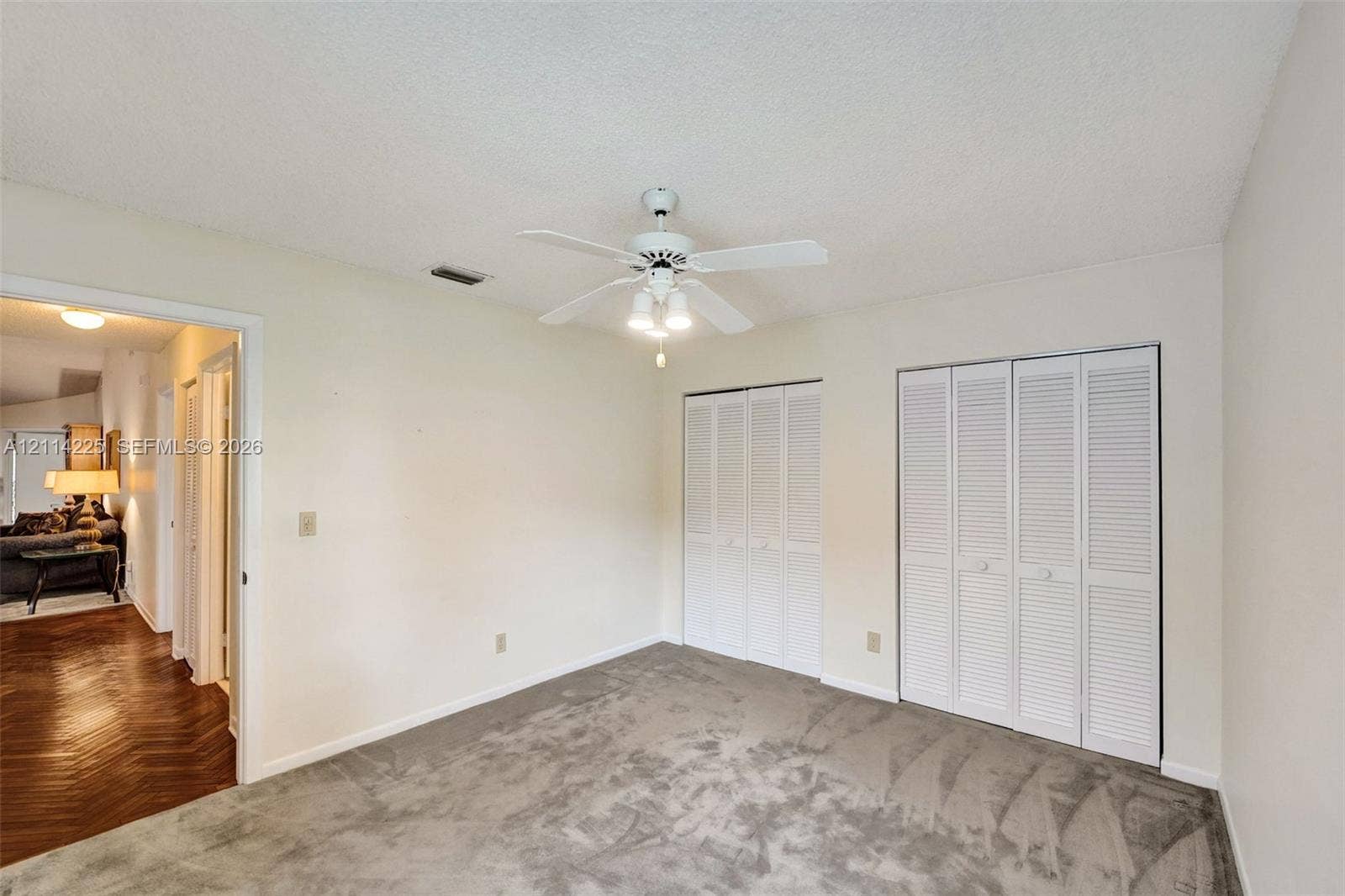 5741 SW 88th Terrace, Cooper City, FL 33328 Neutral-toned carpet, dual white louvered-door closets, and a central ceiling fan with multi-bulb light fixture